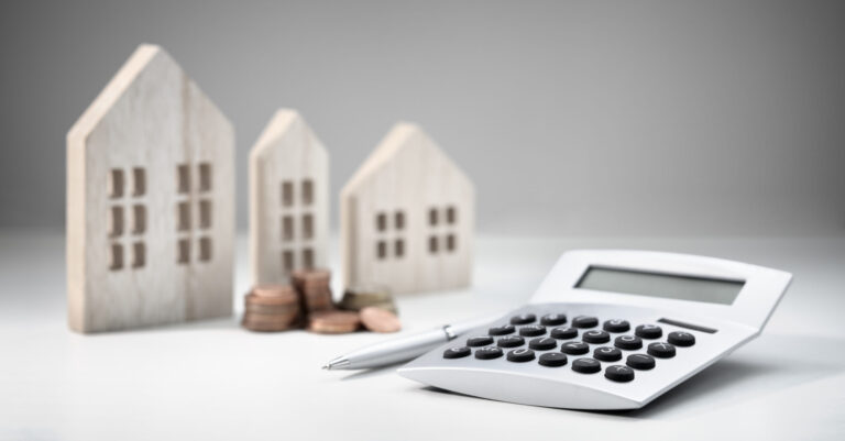 Calculator with wooden house and stack of coins concept for property investment and mortgage loan