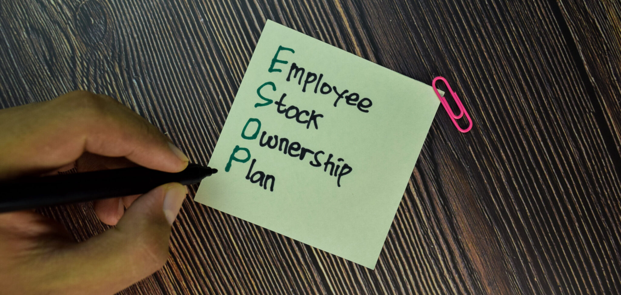 ESOP - Employee Stock Ownership Plan write on sticky note isolated on Wooden Table. Business concept